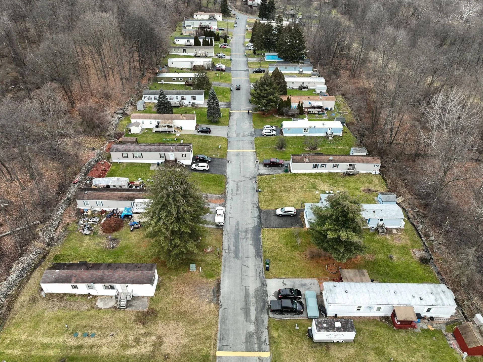 Aerial view of a tree-lined mobile home park with houses along a straight road