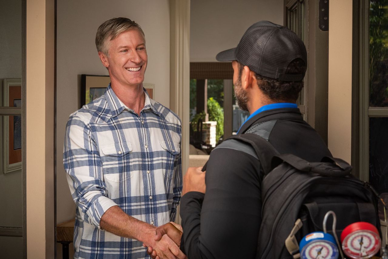 A homeowner greeting an HVAC technician at the door