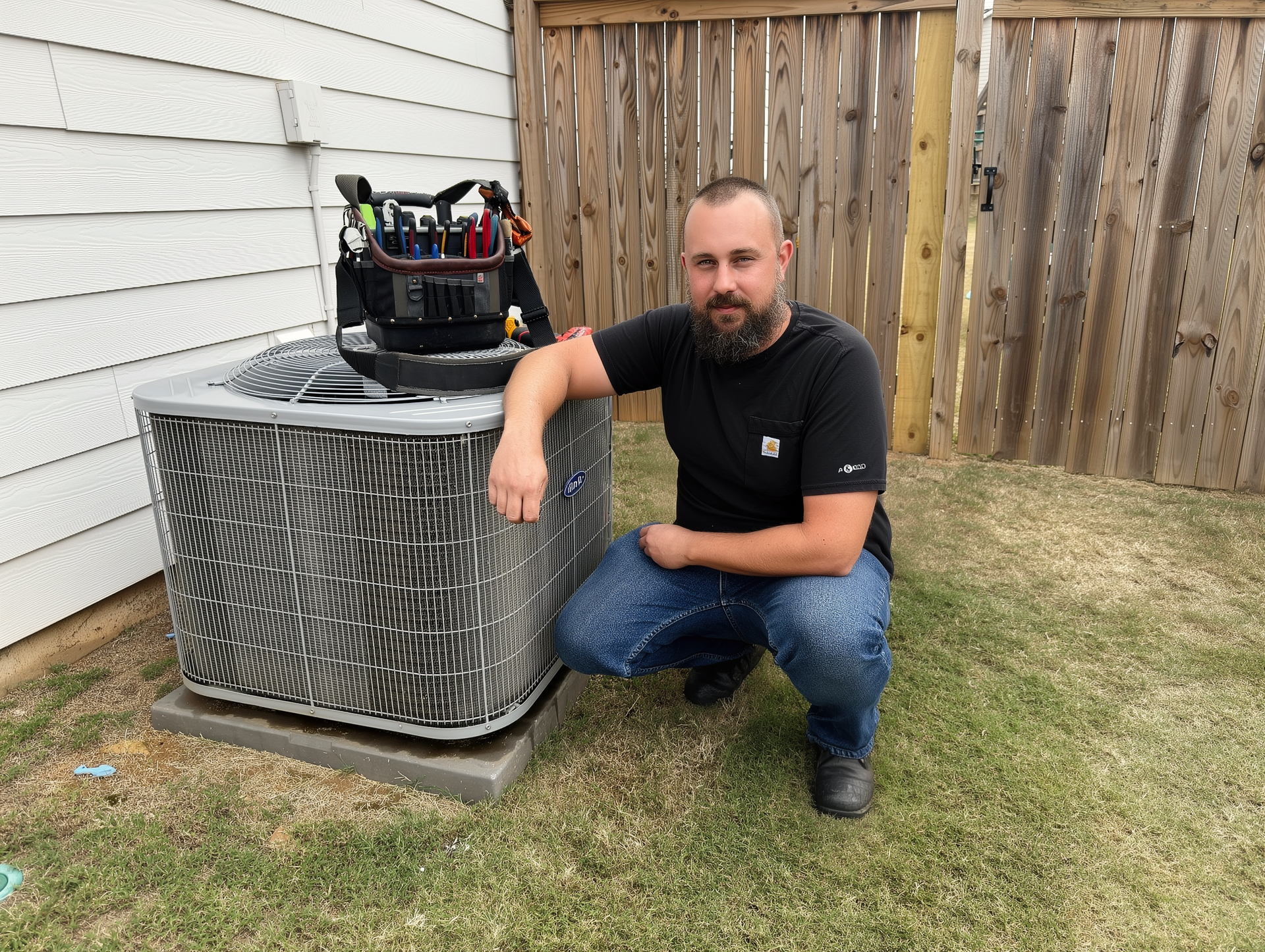 Jake Parks, owner of Radiant Air Systems, kneeling next to an AC condenser