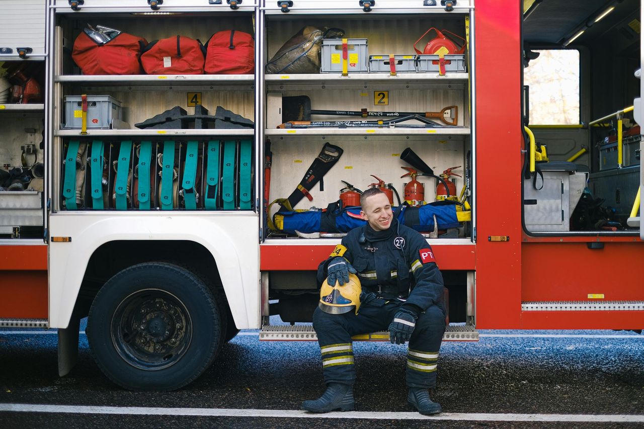 A firefighter resting beside a fire truck