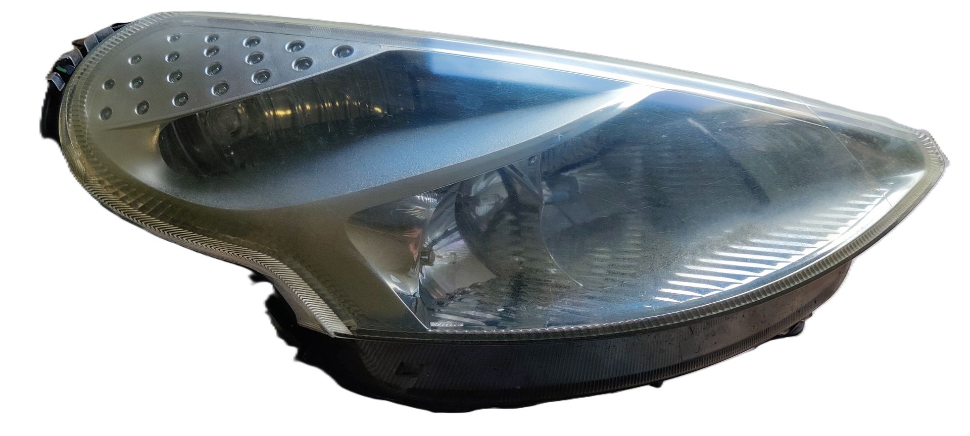Een enkele autokoplampunit met een heldere lens en een donkere behuizing tegen een witte achtergrond.