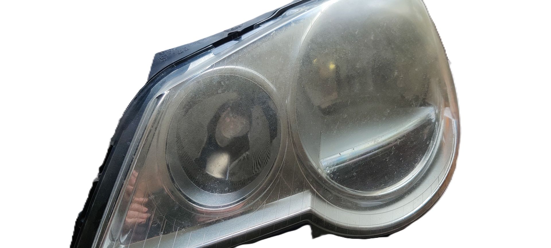 Een ietwat wazige koplampunit met dubbele lens, bestaande uit ronde behuizingen, tegen een effen witte achtergrond.