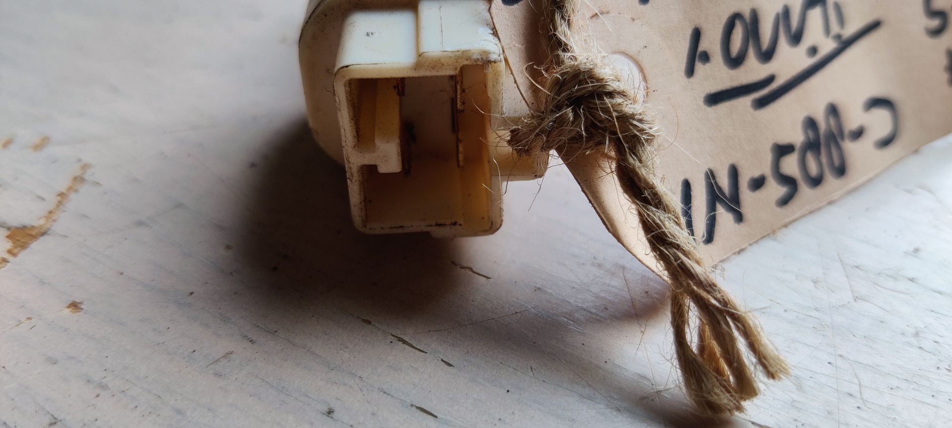 Een beige, cilindrische plastic ontstekingsknop voor een gastoestel, met een kleine zwarte drukknop aan één uiteinde.