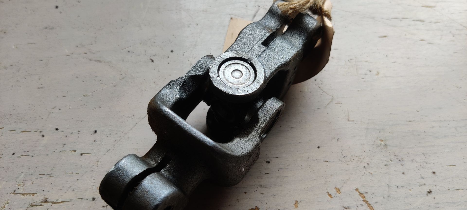 Een donkermetalen kruiskoppelingsstuk tegen een witte achtergrond.