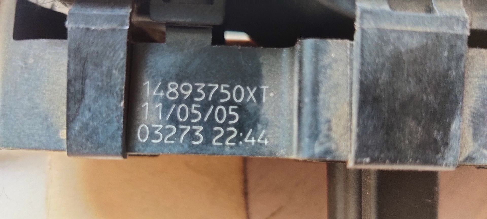 Een zwarte elektrische schakelaar voor een enkel autoraam met een handgeschreven identificatielabel eraan bevestigd.