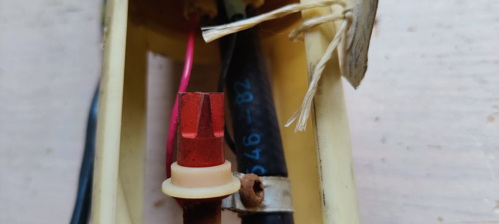 Een crèmekleurige brandstofpompeenheid voor auto's met een bedrade connector en een aangehecht papieren label.