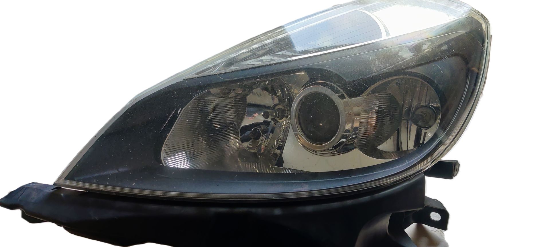 Een zwarte autokoplampunit met een heldere lens en interne reflectorbehuizing op een effen witte achtergrond.