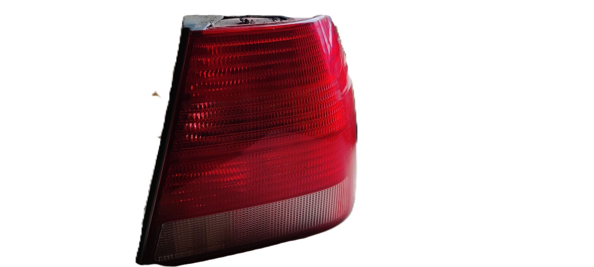 Een rode autoachterlichtunit met een transparant lensgedeelte aan de onderkant, geïsoleerd tegen een witte achtergrond.