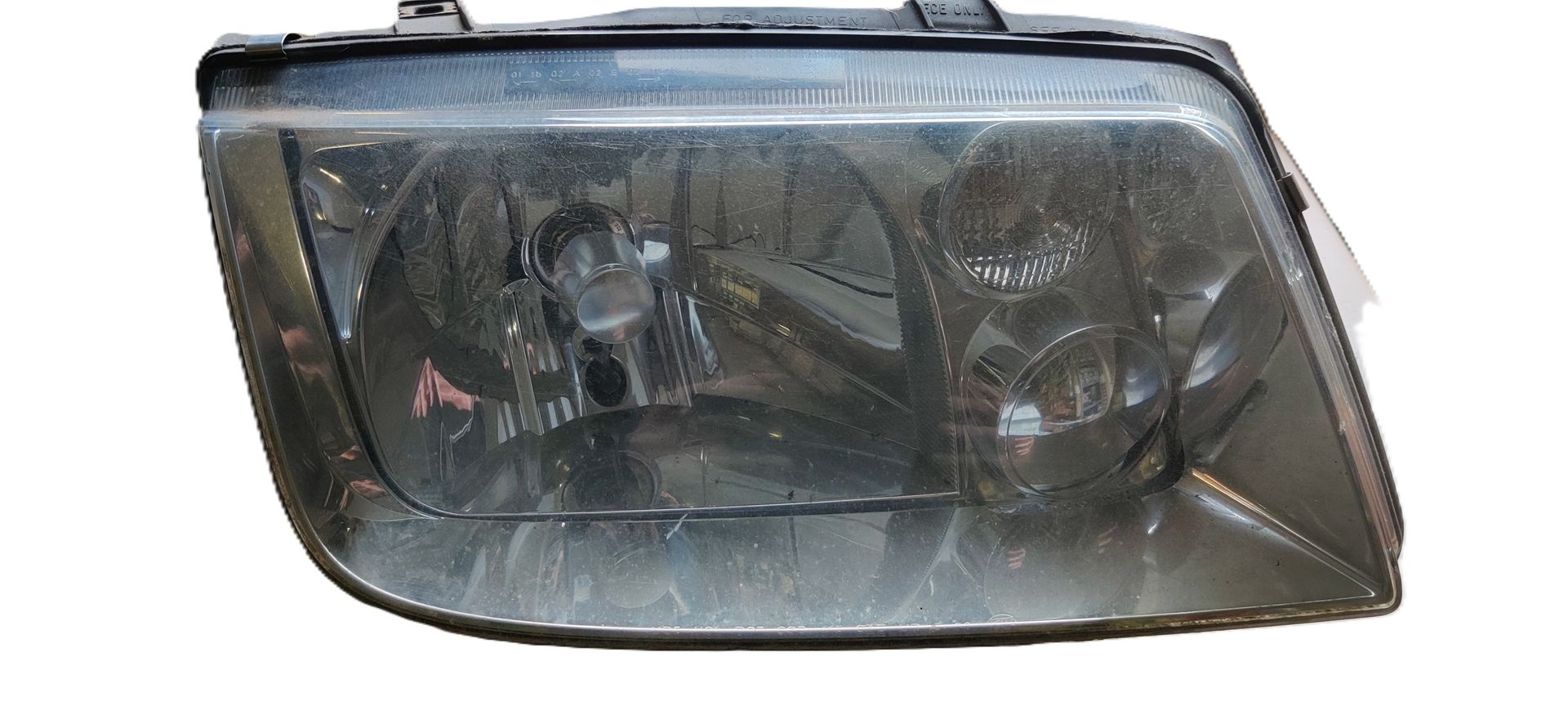 Een donker getinte, rechthoekige autokoplampunit met een heldere lens en interne reflectorkappen.
