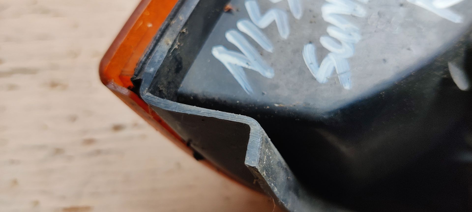 Amberkleurig knipperlichtlensje voor auto's met een gestructureerd oppervlak en twee zichtbare schroefgaten.