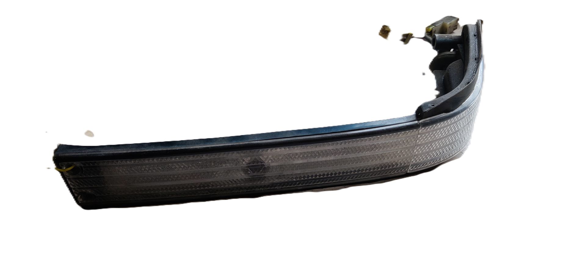 Een zwarte, rechthoekige zijmarkeringslichtunit voor auto's met een lens met textuur, geïsoleerd tegen een witte achtergrond.