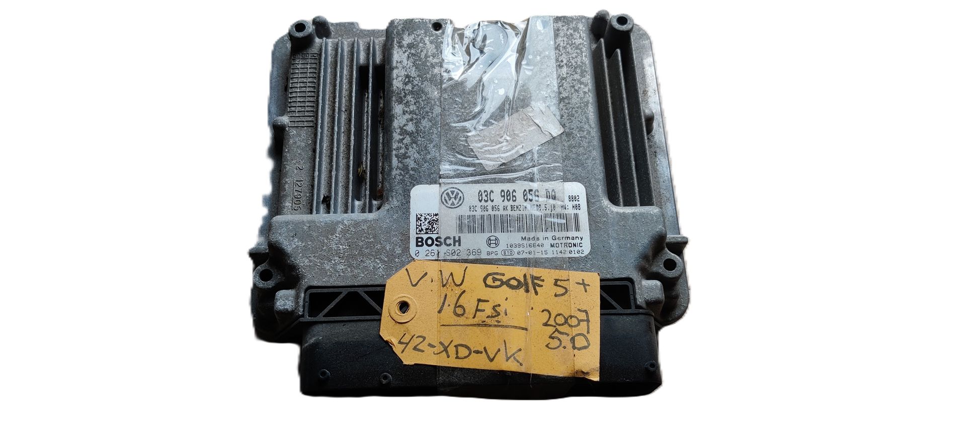 Een grijze ECU (Engine Control Unit) van een auto met een handgeschreven geel identificatielabel, op een witte achtergrond.