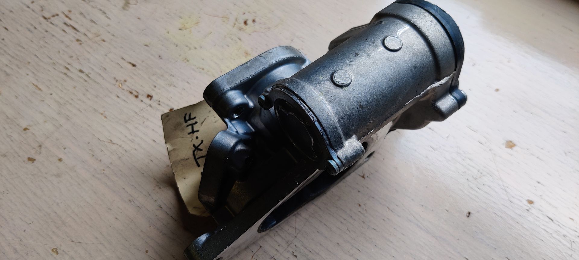 Een EGR-klep voor een automotor met een metallic afwerking en een montageflens met drie bouten.