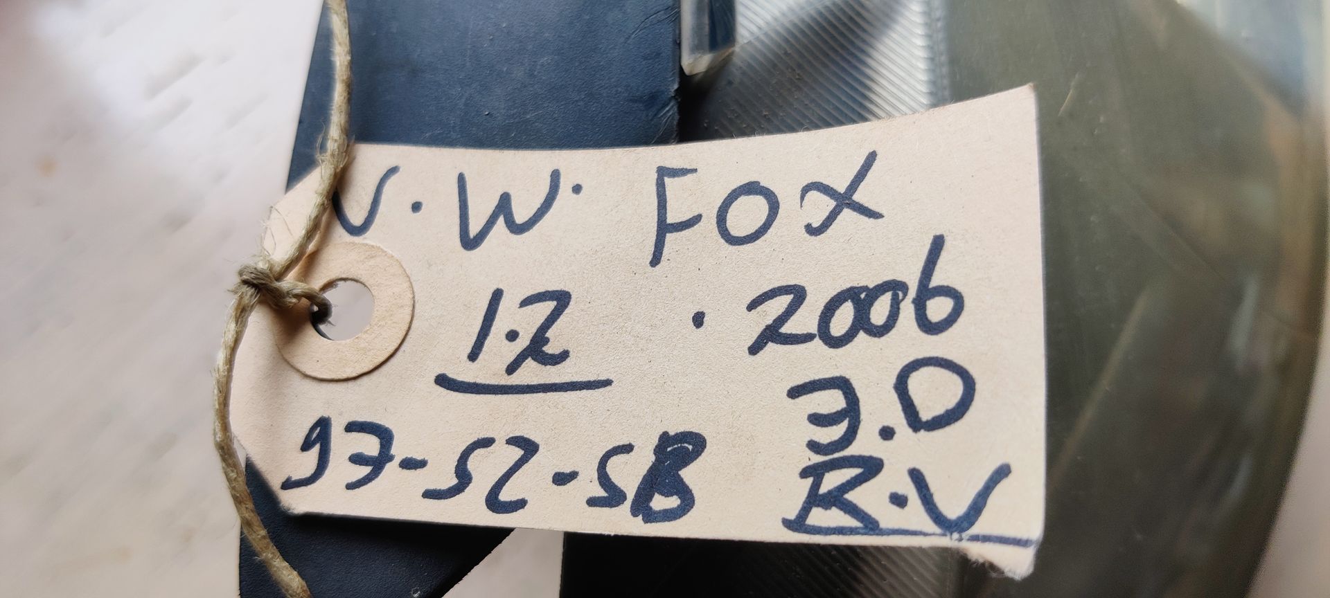 Een enkele zilverkleurige en zwarte autokoplampunit, van voren gezien tegen een witte achtergrond.