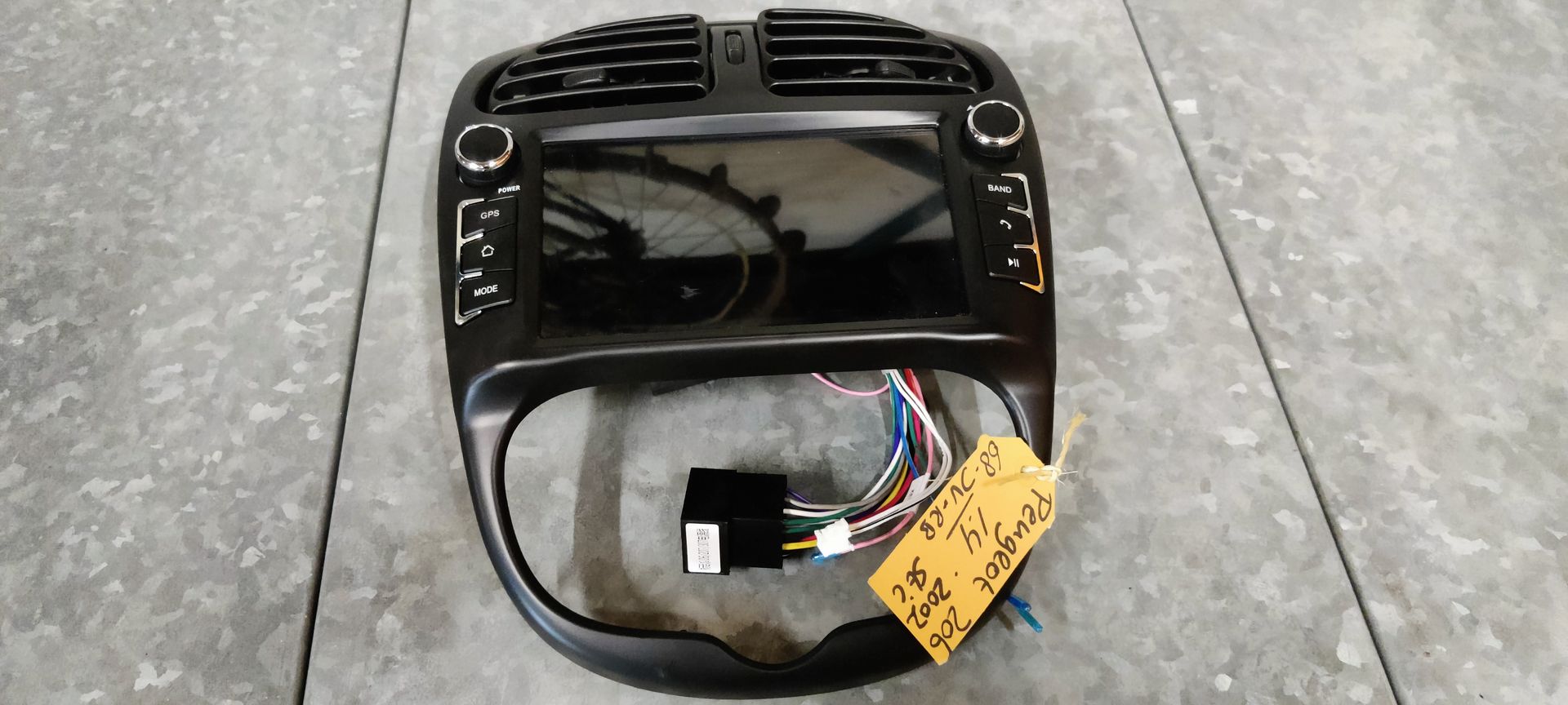 Een zwart autodashboard met middenconsole, twee ventilatieopeningen, een geïntegreerd scherm en bedieningsknoppen.