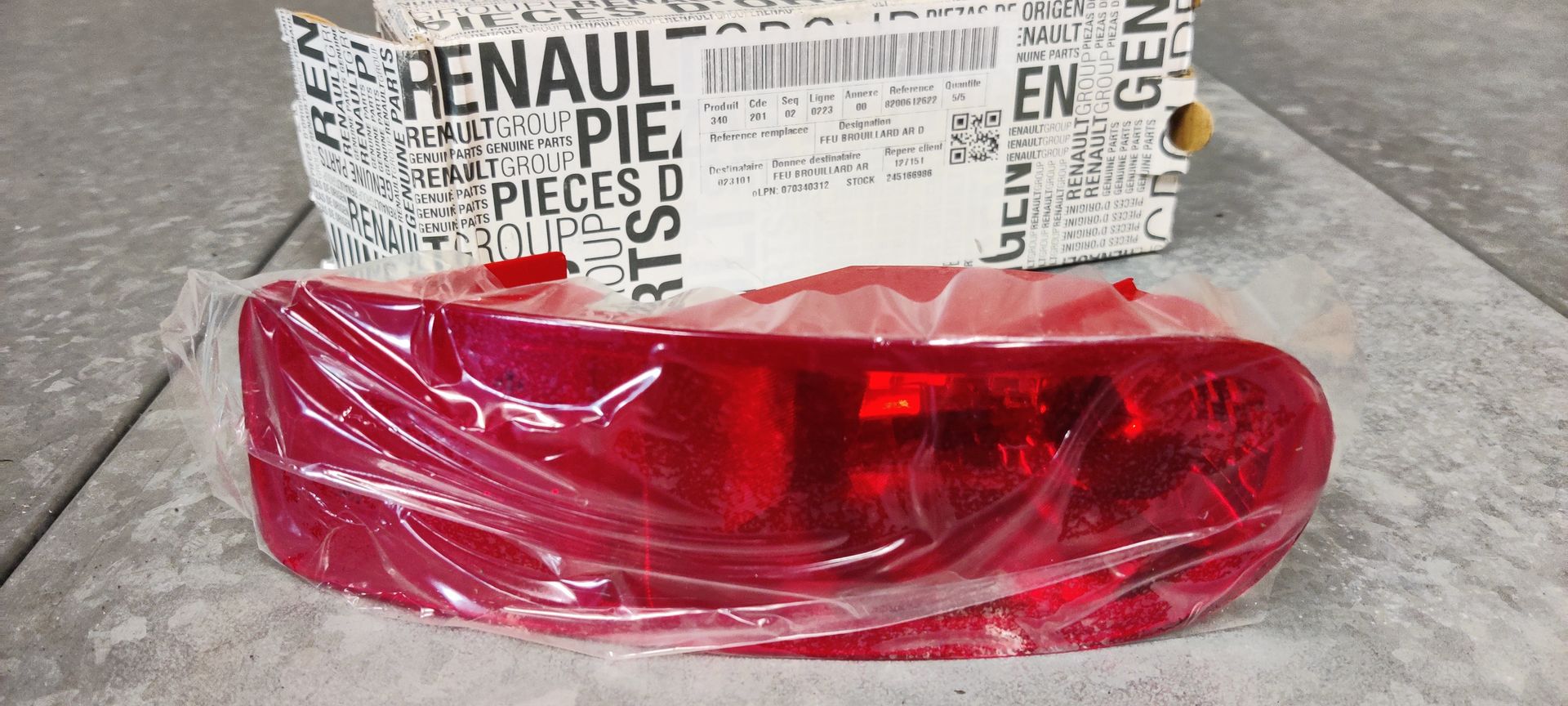 Een nieuw rood Renault-achterlicht in een beschermende plastic zak, dat voor de originele merkverpakking staat.