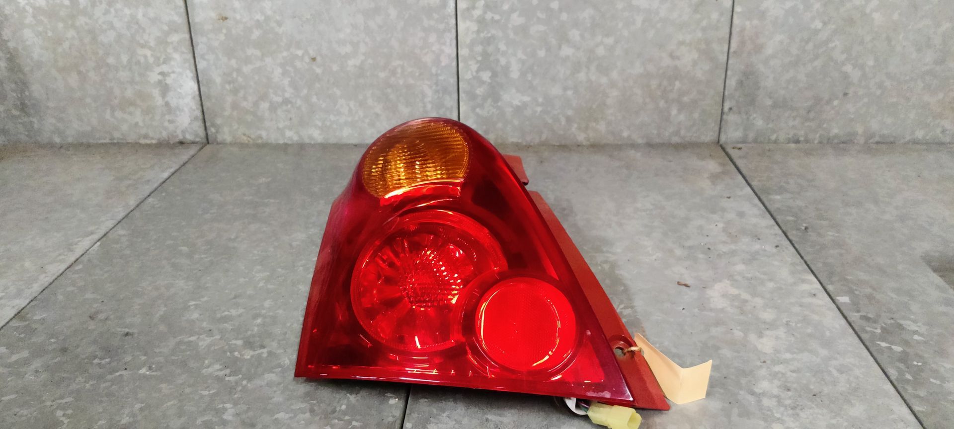 Een rode en amberkleurige achterlichtunit van een aftermarket-auto, geïsoleerd tegen een neutrale grijze achtergrond.
