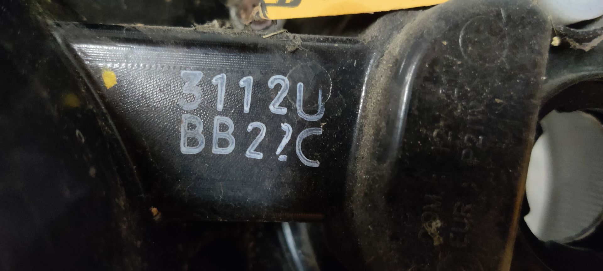 Een achterlichtunit van een auto op een grijze vloer, met rode, gele en transparante ronde lichtsegmenten.