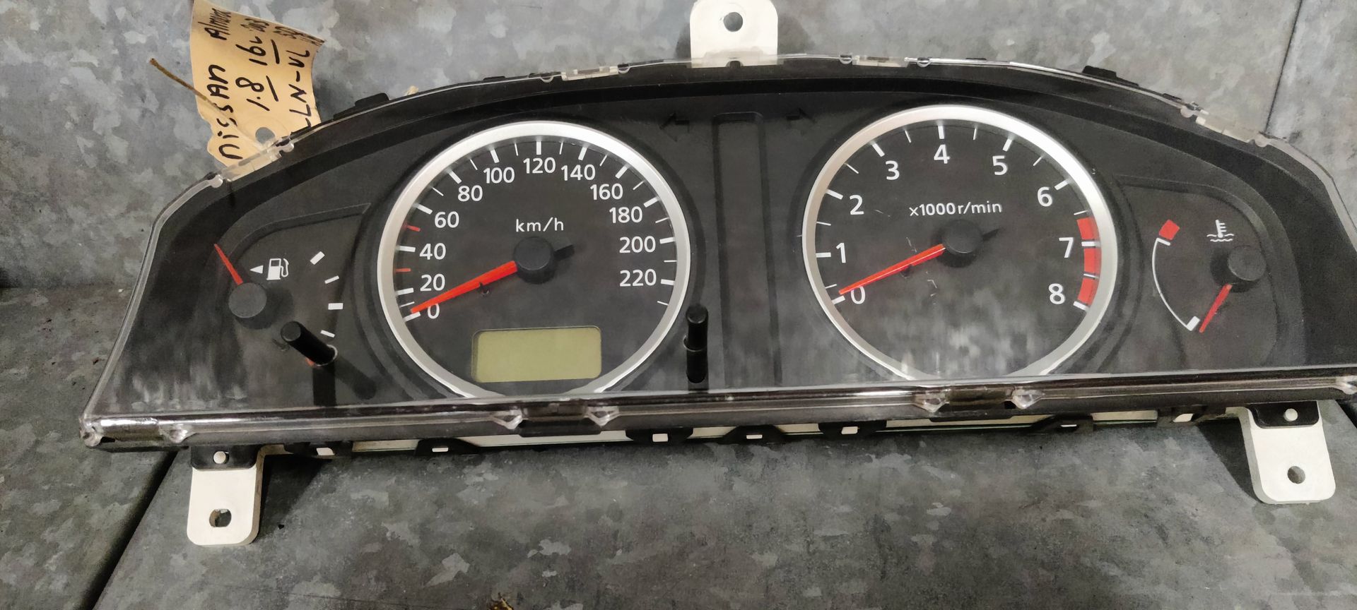 Een instrumentenpaneel van een auto met een snelheidsmeter, toerenteller en brandstofmeter op een grijze achtergrond.