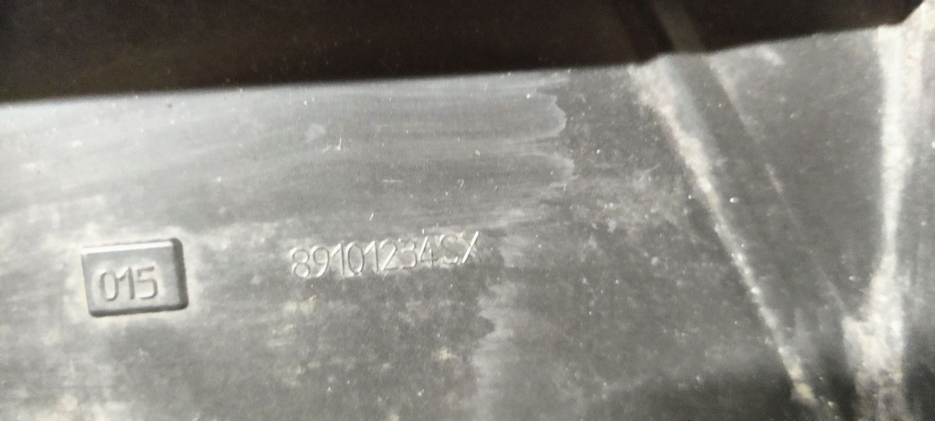 Een enkele autokoplampunit met een zwarte binnenbehuizing en drie ronde glazen lensdelen op een betonnen vloer.