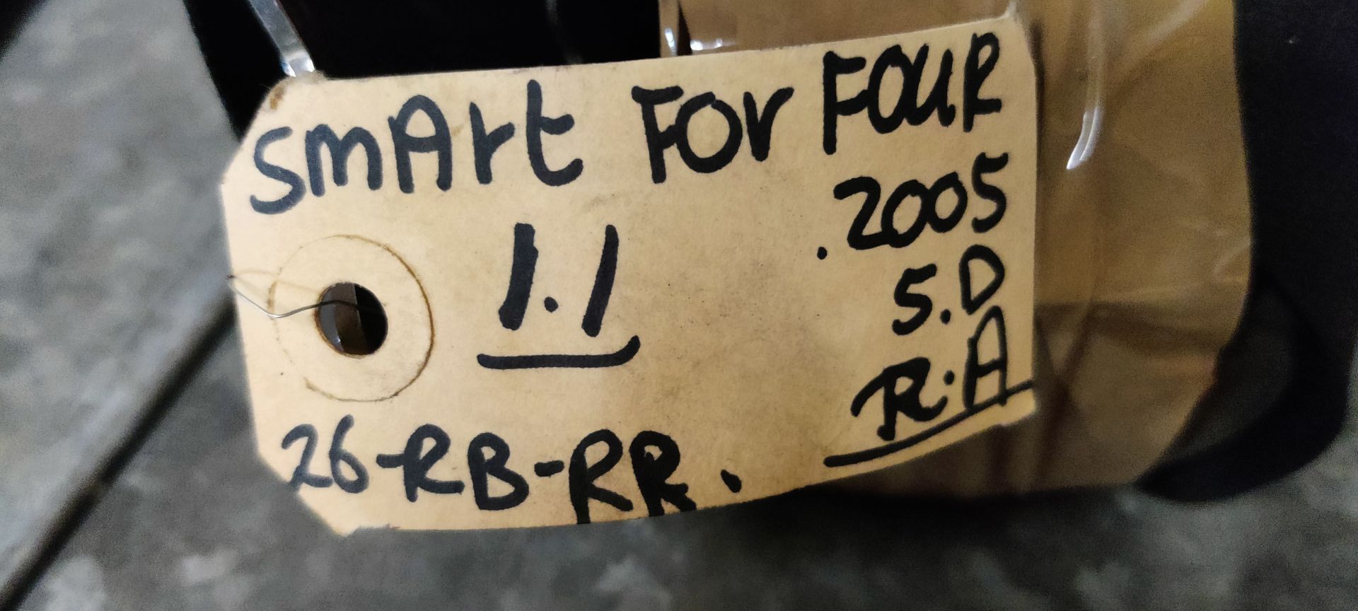 Een zwarte veiligheidsgordel, gedeeltelijk omwikkeld met bruine verpakkingstape, ligt op een grijs metalen oppervlak.