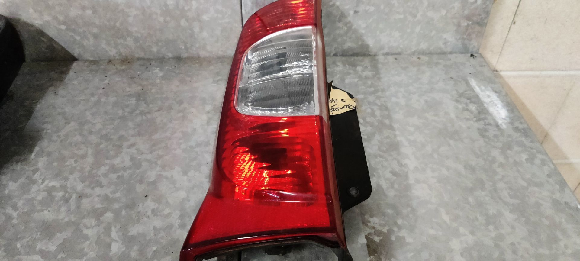 Een rood-witte achterlichtunit van een auto, gemonteerd op een metalen ondergrond.