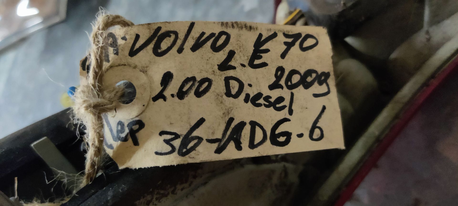 Een rode en transparante achterlichtunit van een auto ligt op een grijze betonnen vloer.