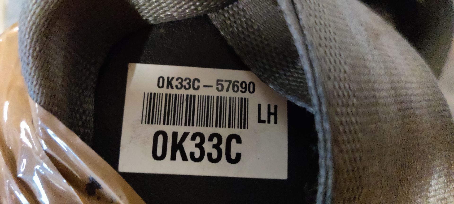 Een beige veiligheidsgordel, omwikkeld met verpakkingstape en voorzien van een geel, handgeschreven identificatielabel.