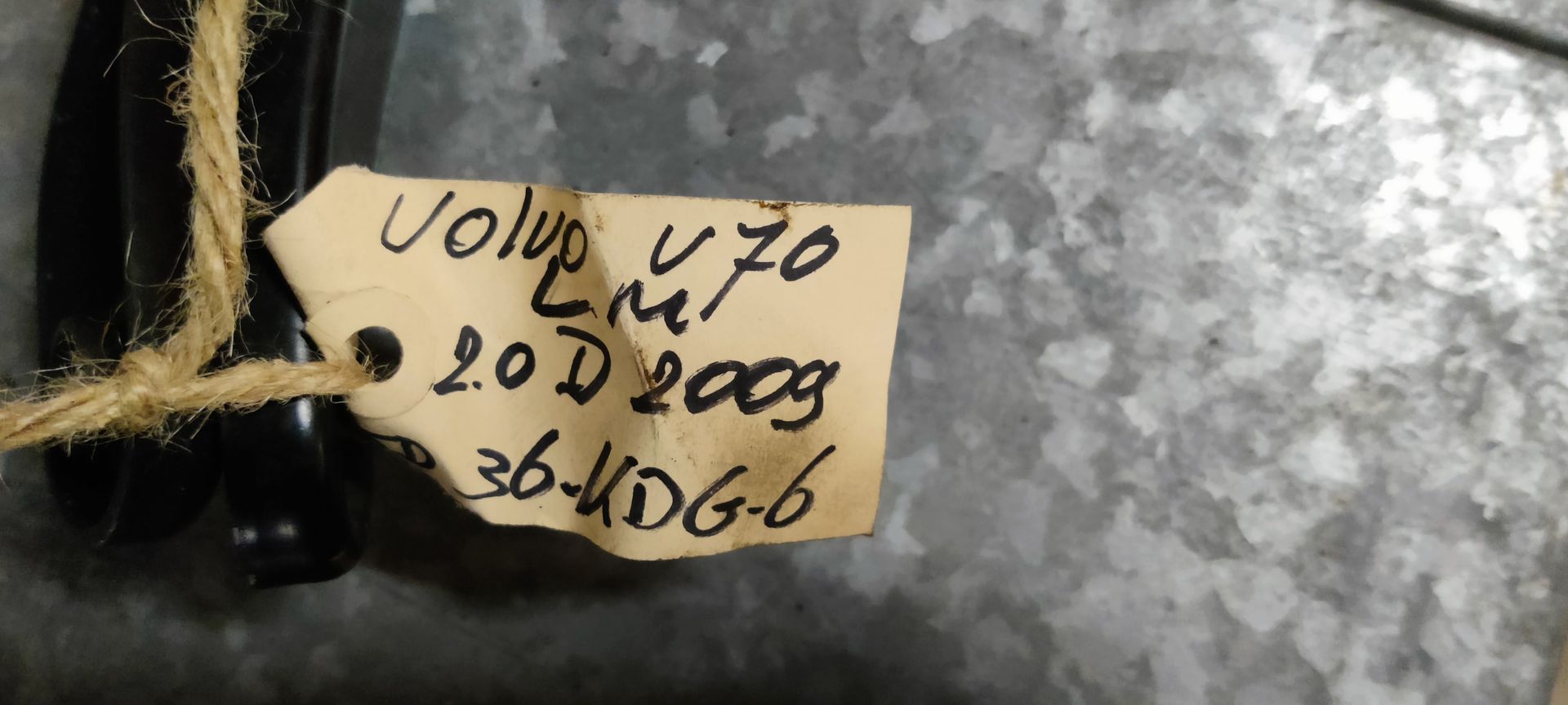 Twee zwarte metalen ruitenwisserarmen liggen op een grijze betonnen ondergrond.