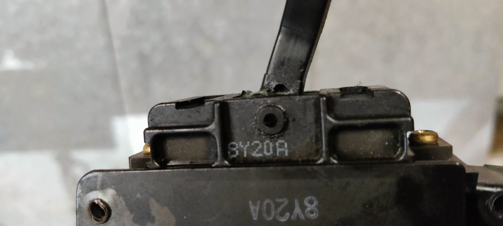 Een zwarte stuurkolomschakelaar voor een Nissan Almera, met een handgeschreven label eraan.