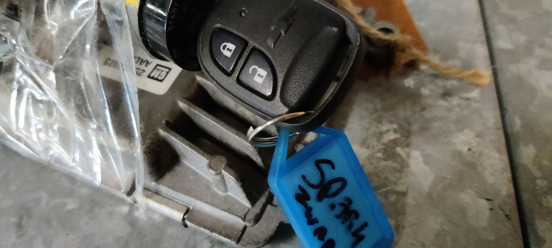 Een elektronisch gasklephuisonderdeel met elektrische aansluitingen, dat op een grijze tegelvloer ligt.