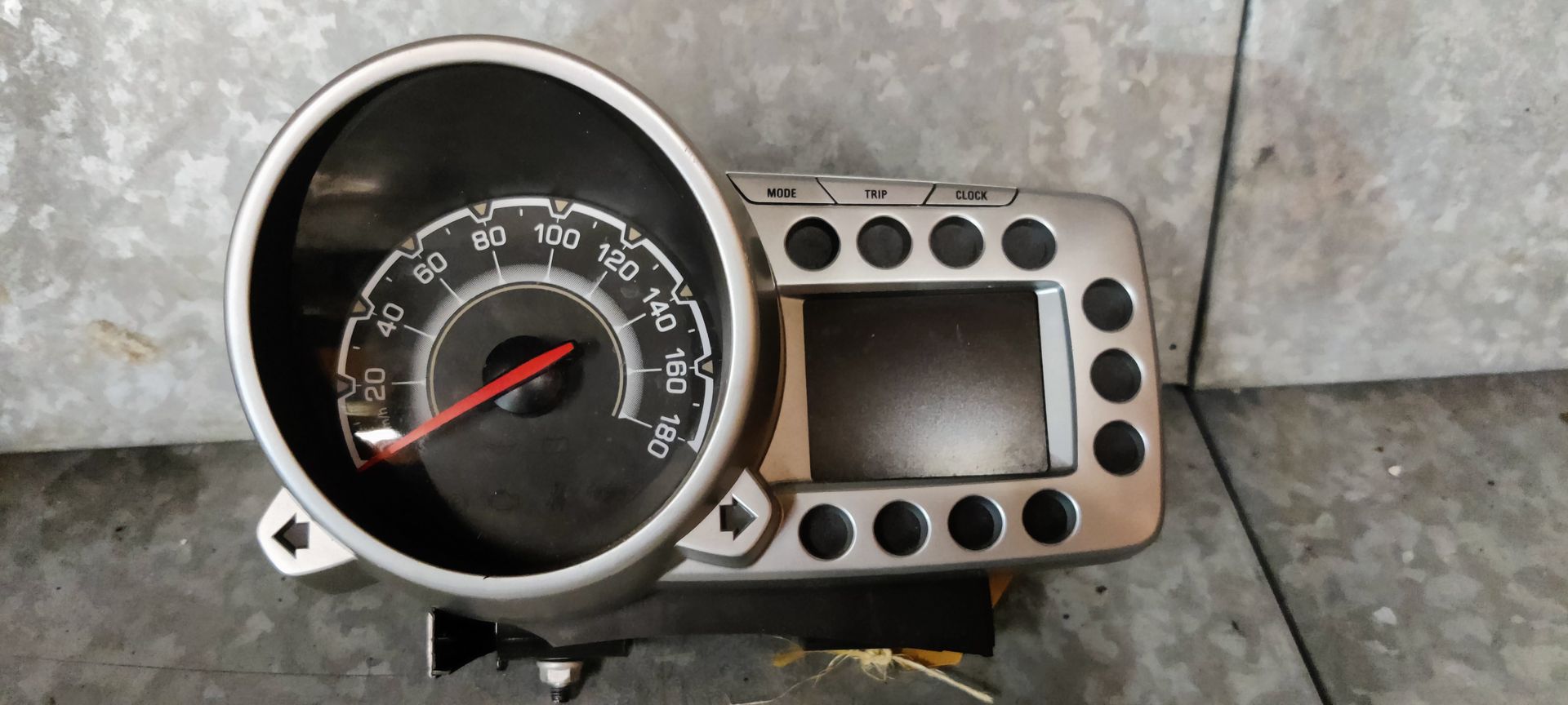 Een grijs, afgerond instrumentenpaneel voor autosnelheidsmeters met één wijzerplaat en een aangrenzend digitaal display.