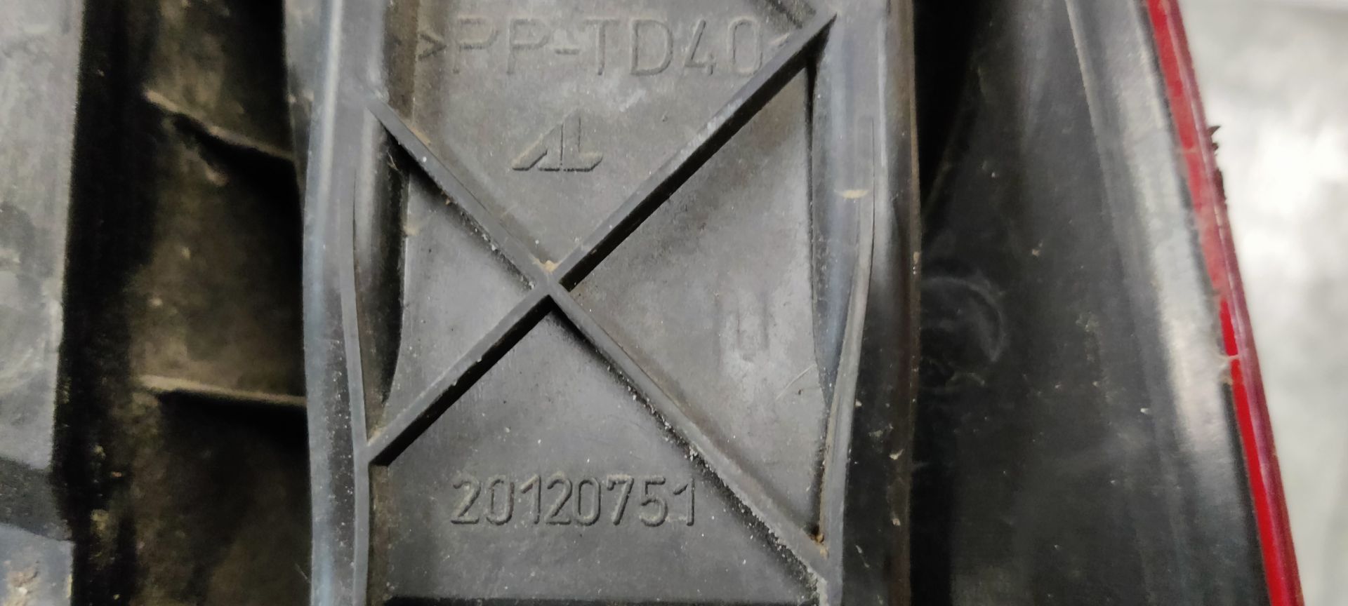 Een rode en transparante achterlichtunit van een auto, van de zijkant gezien, rustend op een grijze betonnen ondergrond.