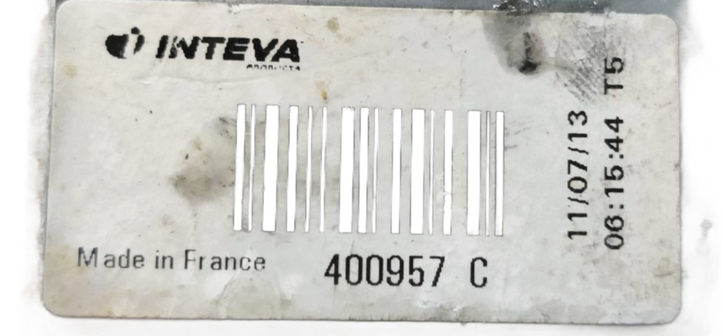 Een zilverkleurige raammechanisme voor auto's, met een zwarte elektromotor en kabel, ligt op een grijs werkblad.