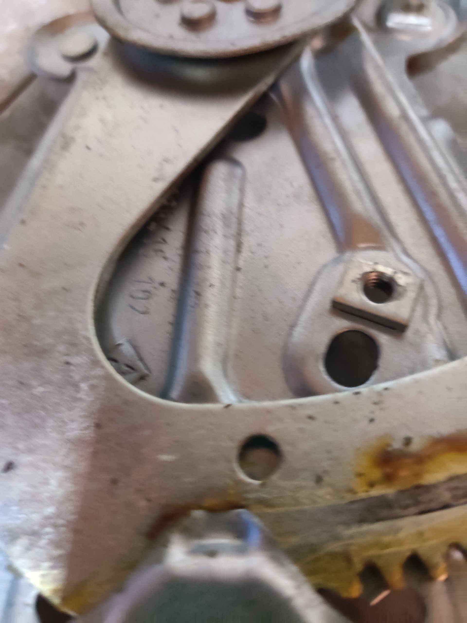 Metalen mechanische constructie met een kabel en label op een grijze betonnen vloer.