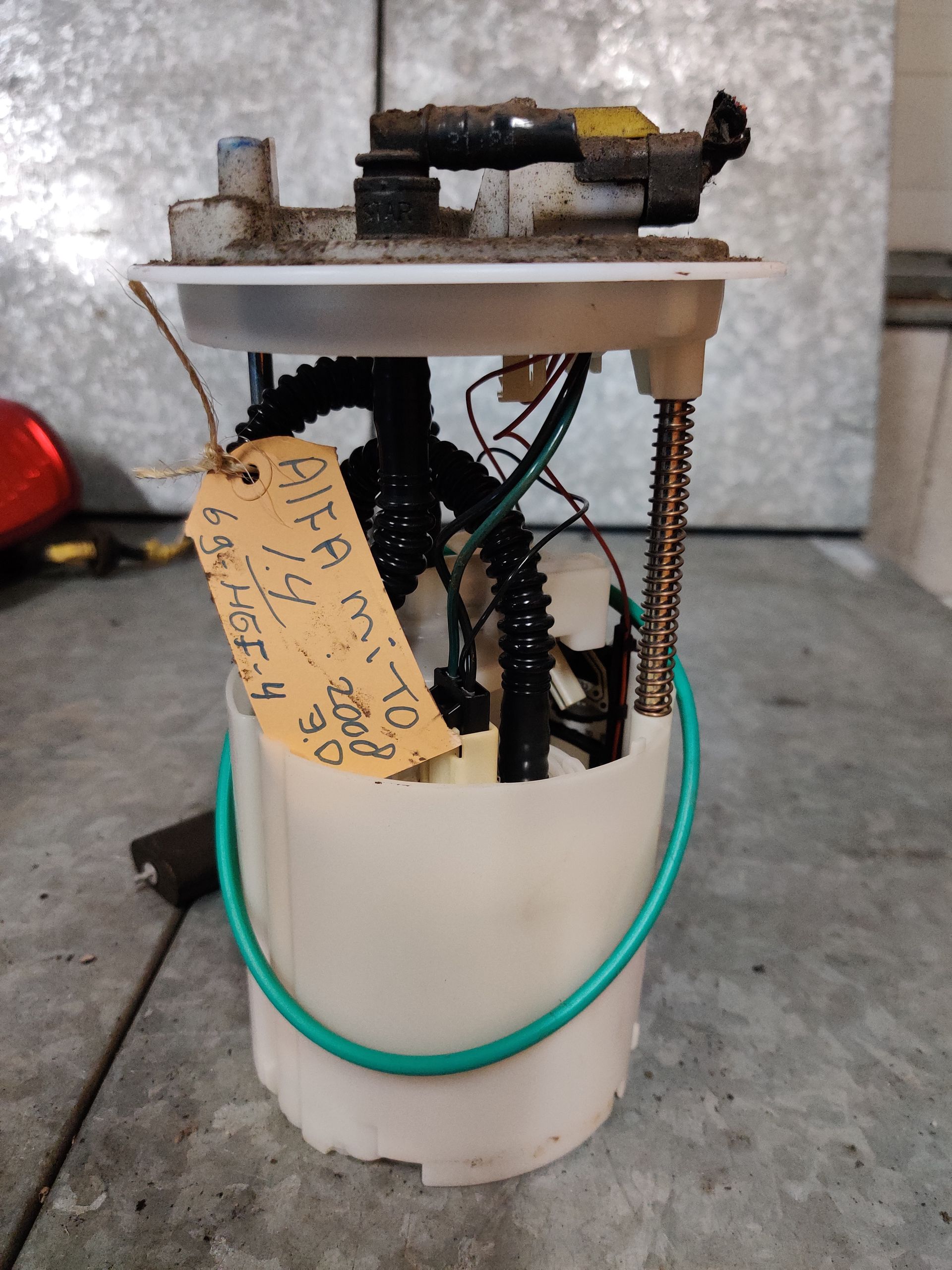 Zelfgemaakt mechanisch apparaat in een witte emmer, met draden, veren en een motor bovenop.