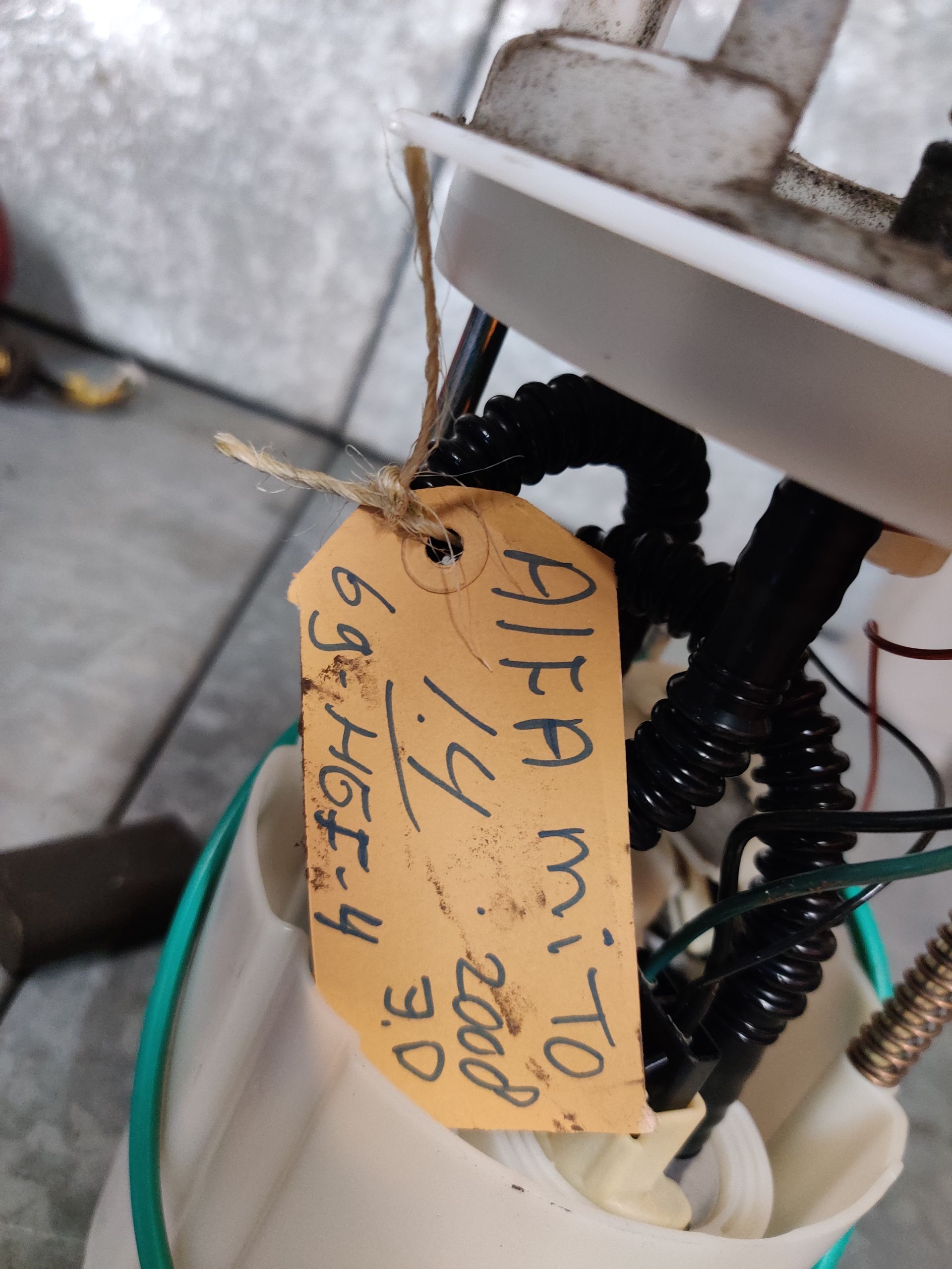 Zelfgemaakt mechanisch apparaat in een witte emmer, met draden, veren en een motor bovenop.