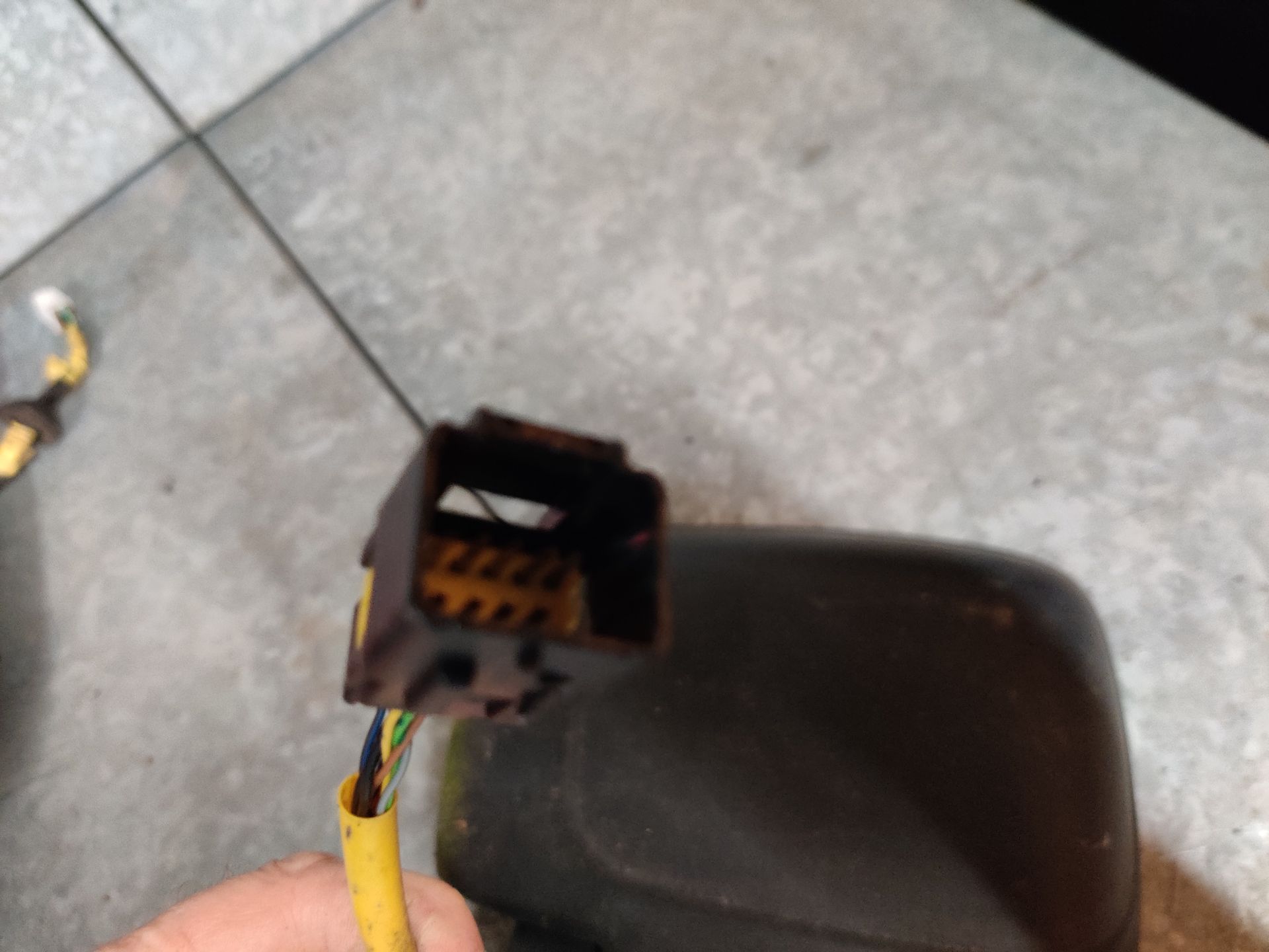 Een Fiat Scudo autospiegel ligt op een betonnen vloer, met blootliggende gele draden.