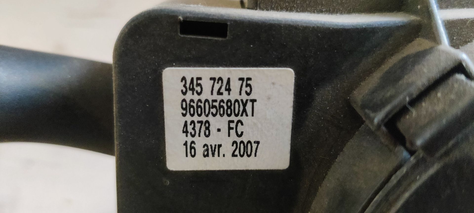 Een zwarte stuurkolomschakelaar met twee bedieningshendels en bijbehorende elektrische bedradingsconnectoren.
