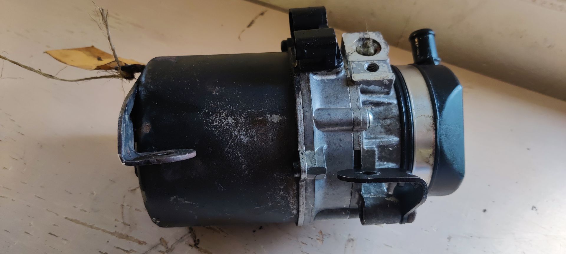 Een elektrische hydraulische stuurbekrachtigingspomp met een zwarte cilindrische behuizing en een metalen pompunit erbovenop.