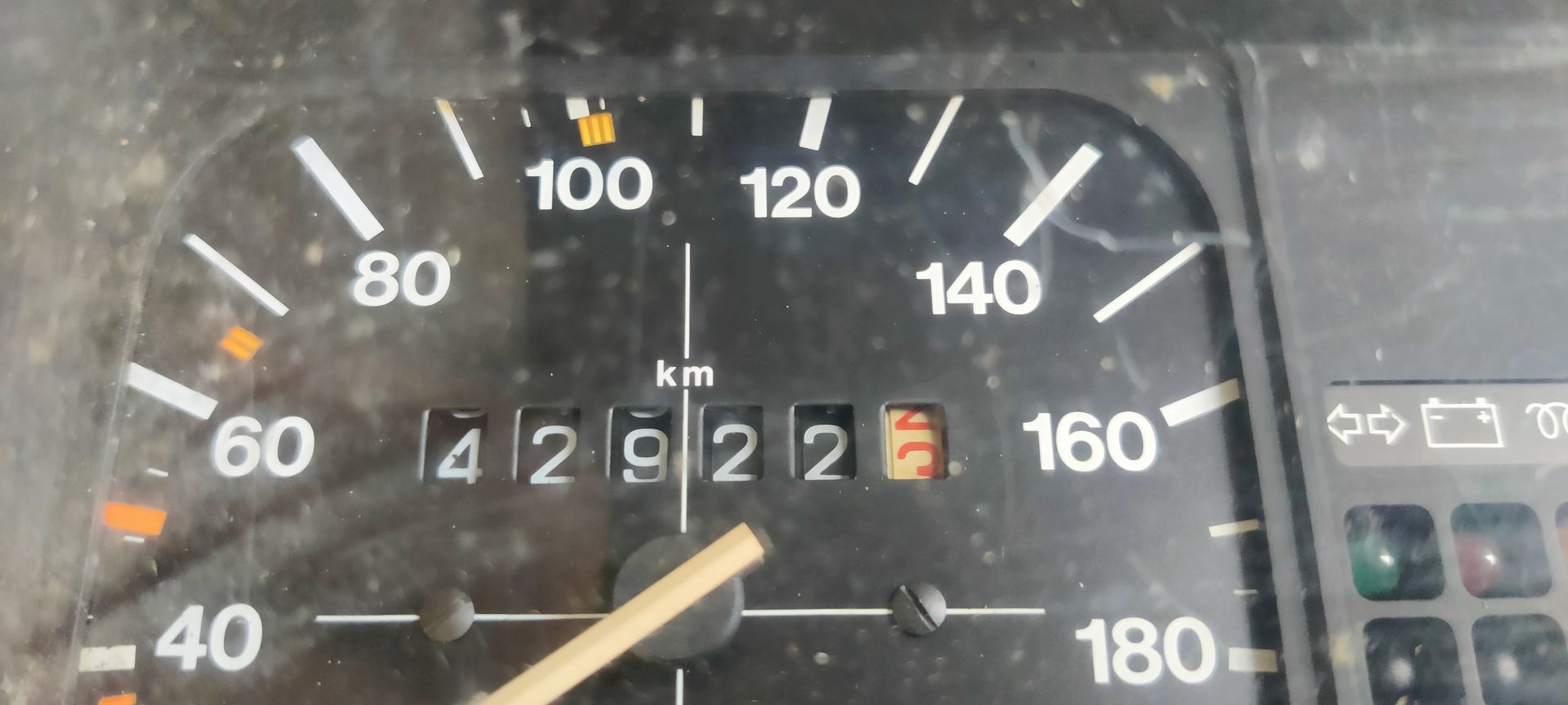 Een stoffige, vintage snelheidsmeter en brandstofmeter met een zwart dashboard en witte markeringen.