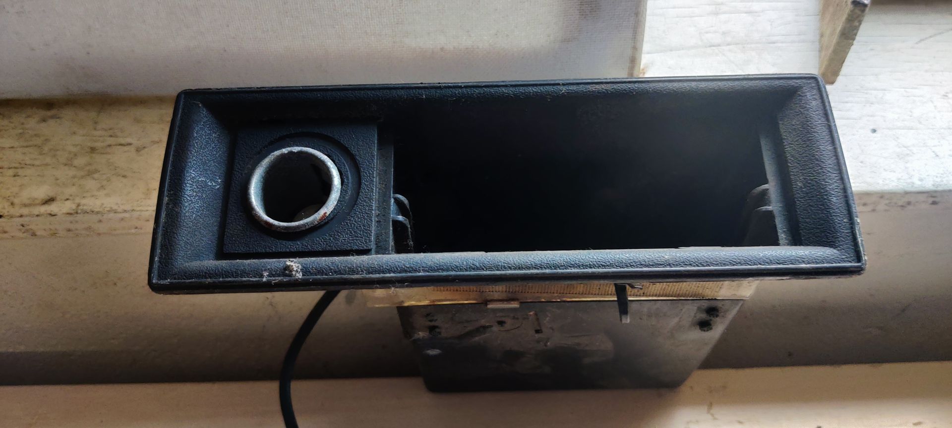 Een zwarte sigarettenaanstekerunit voor een VW Jetta I 1.6D uit 1982 met een bedrade stekker, gezien vanaf de voorkant.