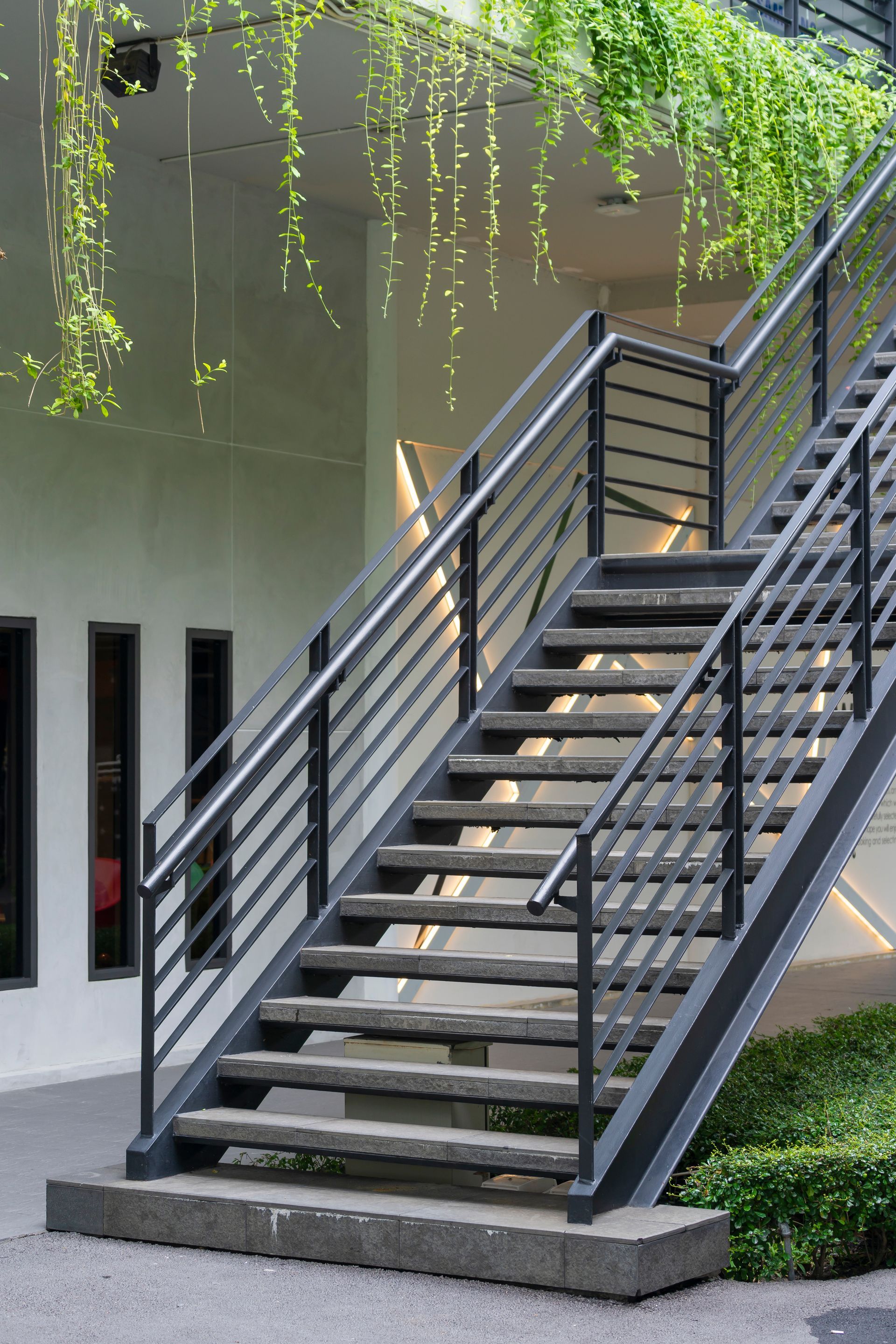 Metal exterior staircase with black handrails and stone steps Metal exterior staircase with black handrails and stone steps