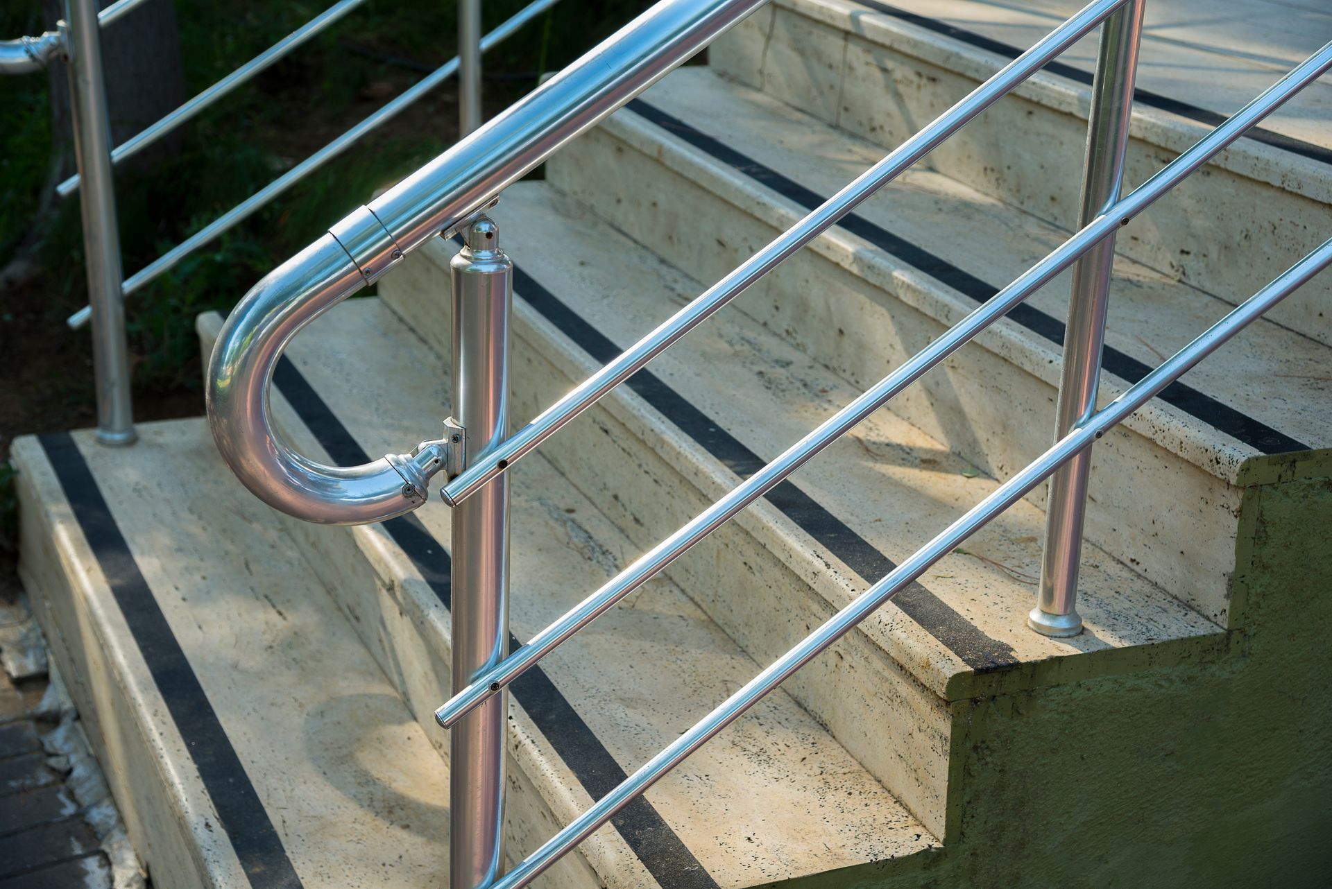 Railing on outdoor concrete stairs with black non-slip strips Railing on outdoor concrete stairs with black non-slip strips