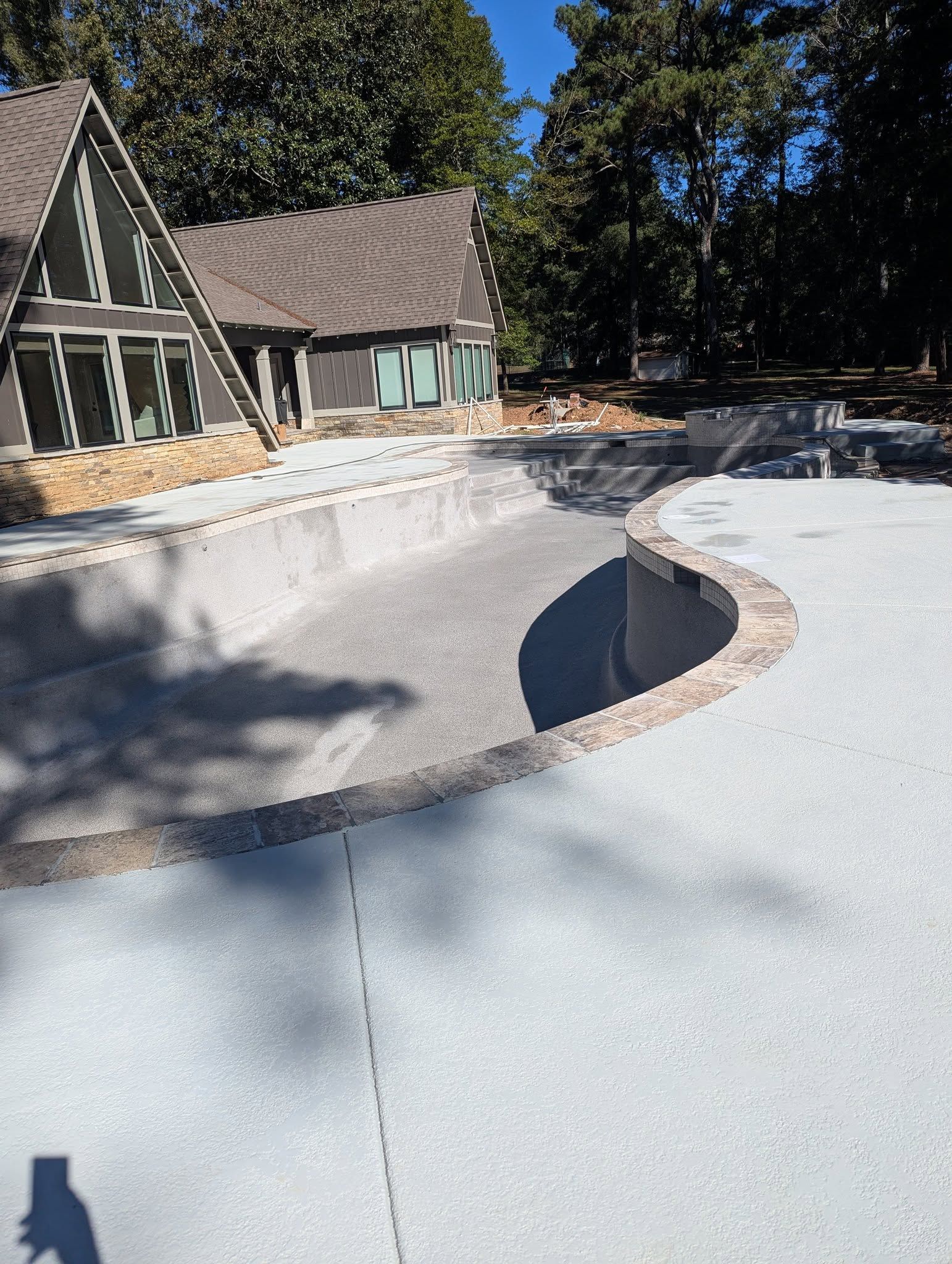 Snow-covered driveway with a curved, cleared path beside a house and trees