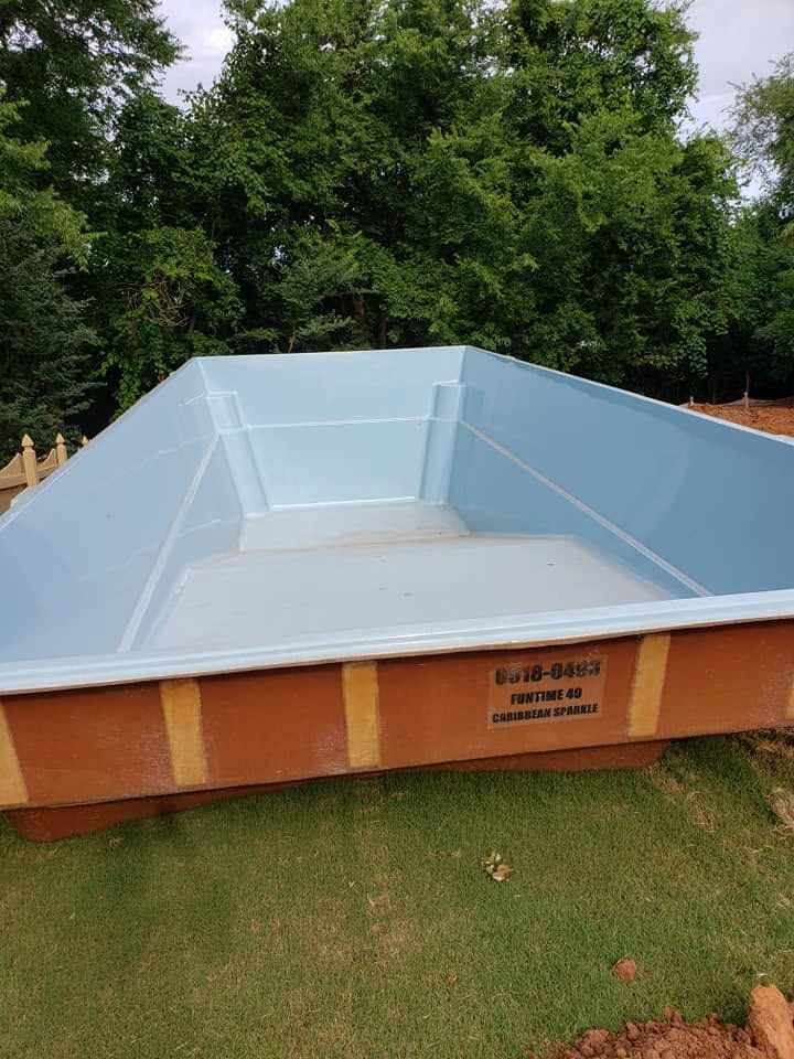 Blue-lined above-ground pool outdoors on grass, with trees in the background