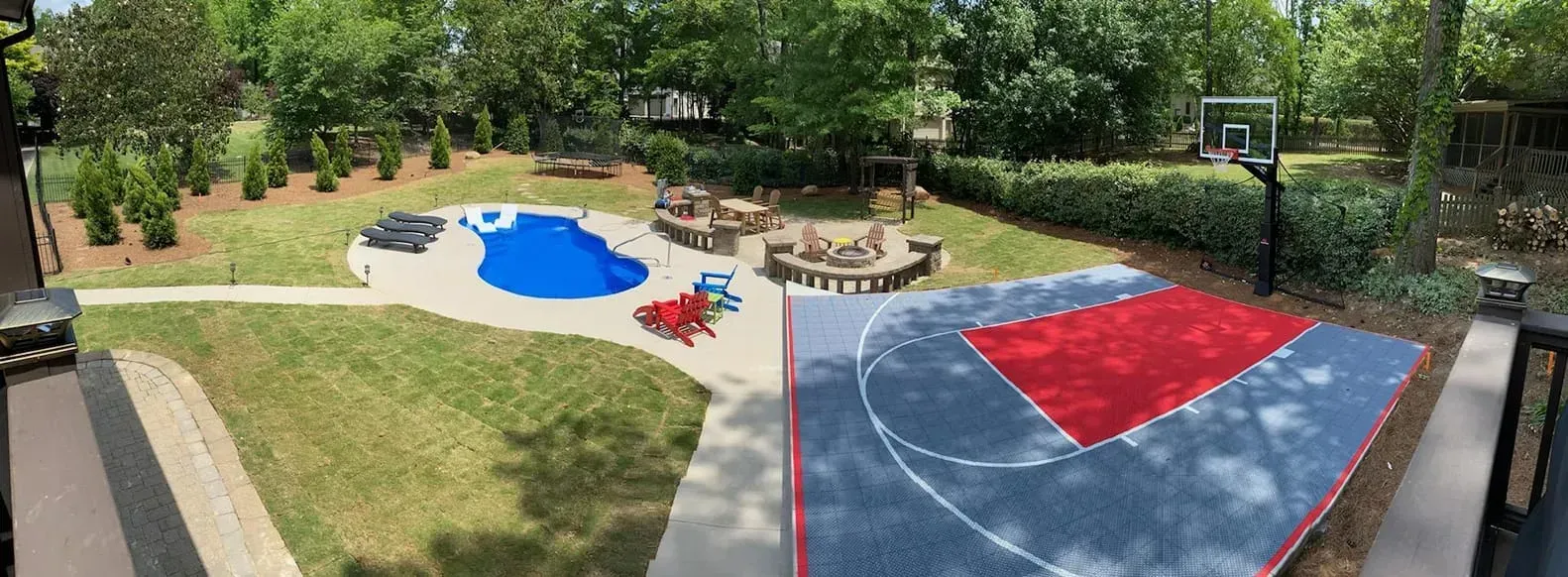 Playground with blue and red climbing surfaces, sandbox, and trees in a park.