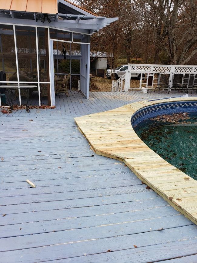 Backyard pool deck with a blue-painted wooden patio and partially covered pool edge