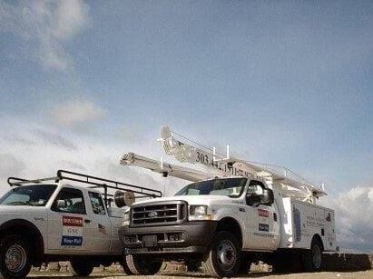 Two utility trucks are parked next to each other on a road. Two utility trucks are parked next to each other on a road.