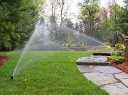 A lawn sprinkler is spraying water on a lush green lawn. A lawn sprinkler is spraying water on a lush green lawn.